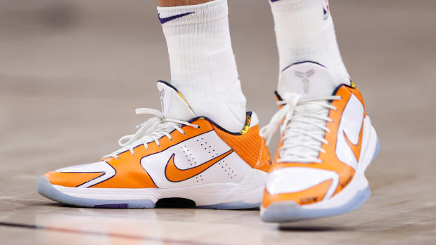 View of Devin Booker's orange and white Nike shoes.